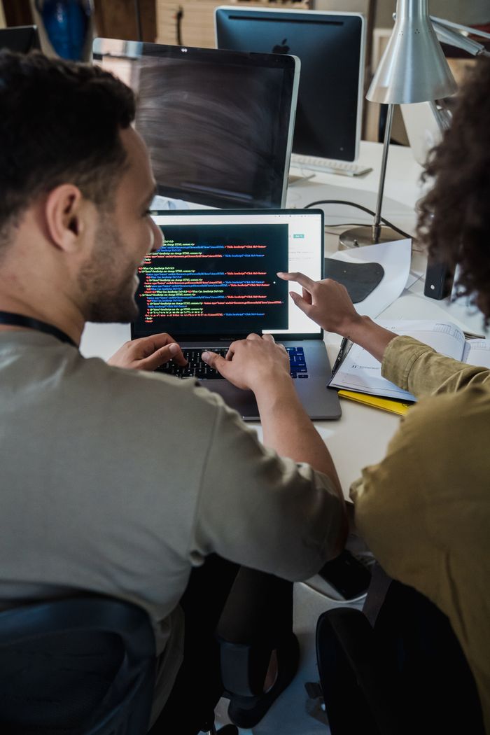 Crafting Captivating Headlines: Your awesome post title goes here Two programmers working together on a laptop, discussing code in a modern office setting.
