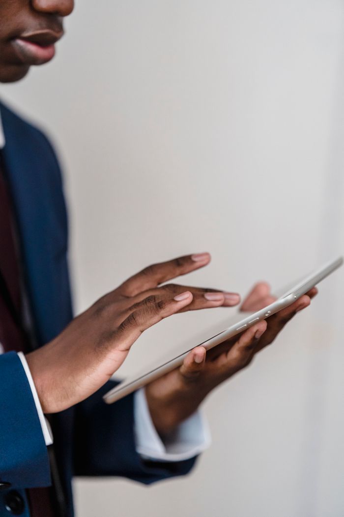 Close-up of a businessman's hands using a digital tablet indoors.